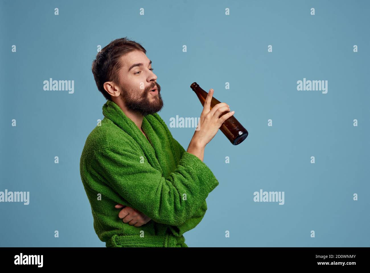 hombre borracho en una bata verde con una botella de cerveza en su mano  sobre un alcohol de fondo azul Fotografía de stock - Alamy