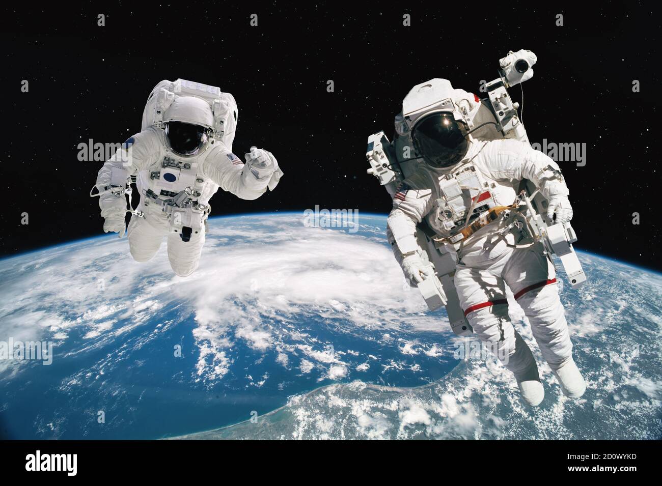 Dos astronautas caminando en el espacio con fondo terrestre. Elementos de esta imagen proporcionados por la NASA. Foto de stock
