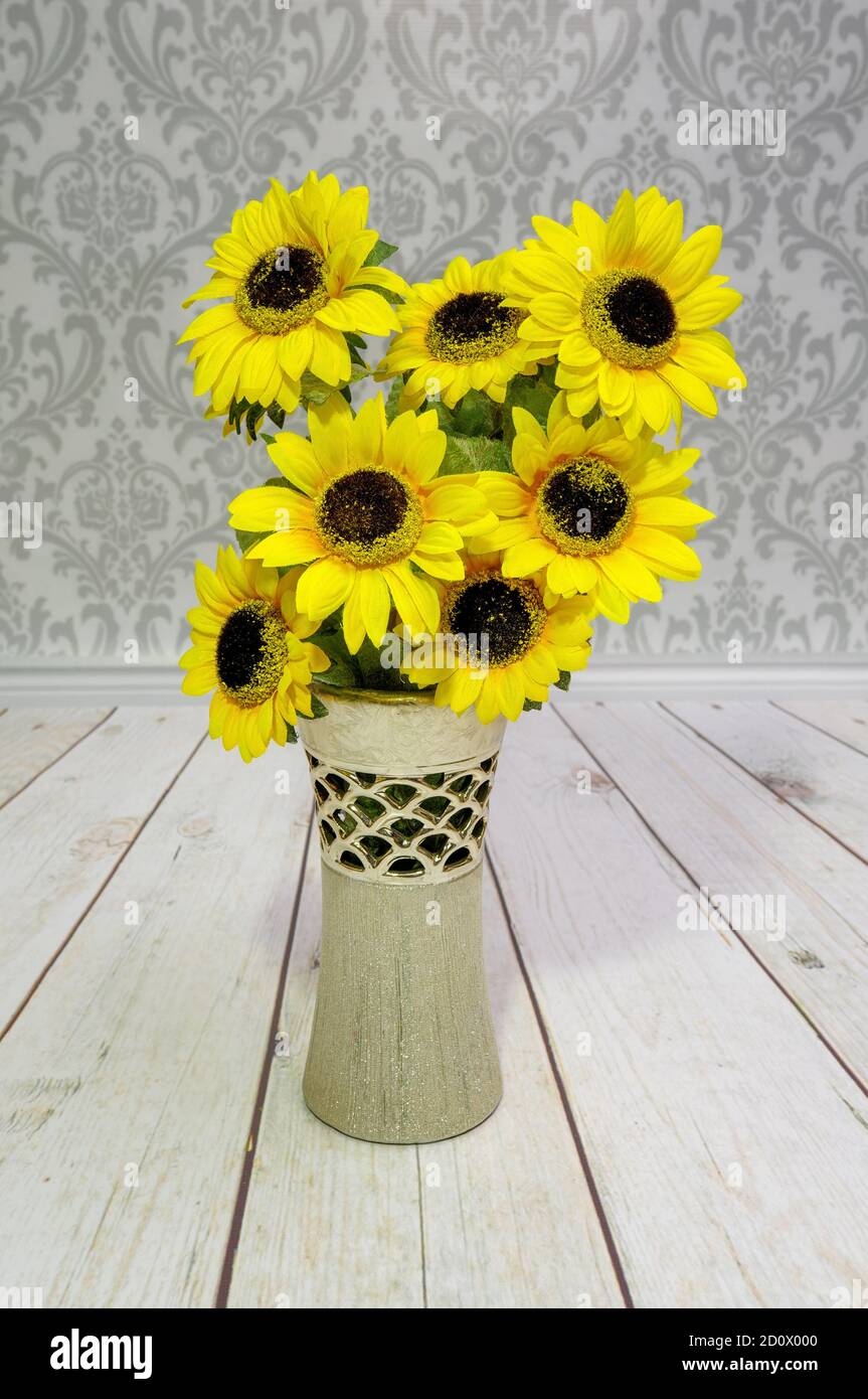 girasoles amarillos, flores artificiales de color en un jarrón decorativo  en el fondo del piso y la pared Fotografía de stock - Alamy