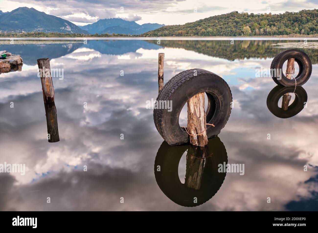 Montañas y neumáticos reflejados en el agua del lago en otoño, Lago di Alserio, Lombardía, Italia Foto de stock