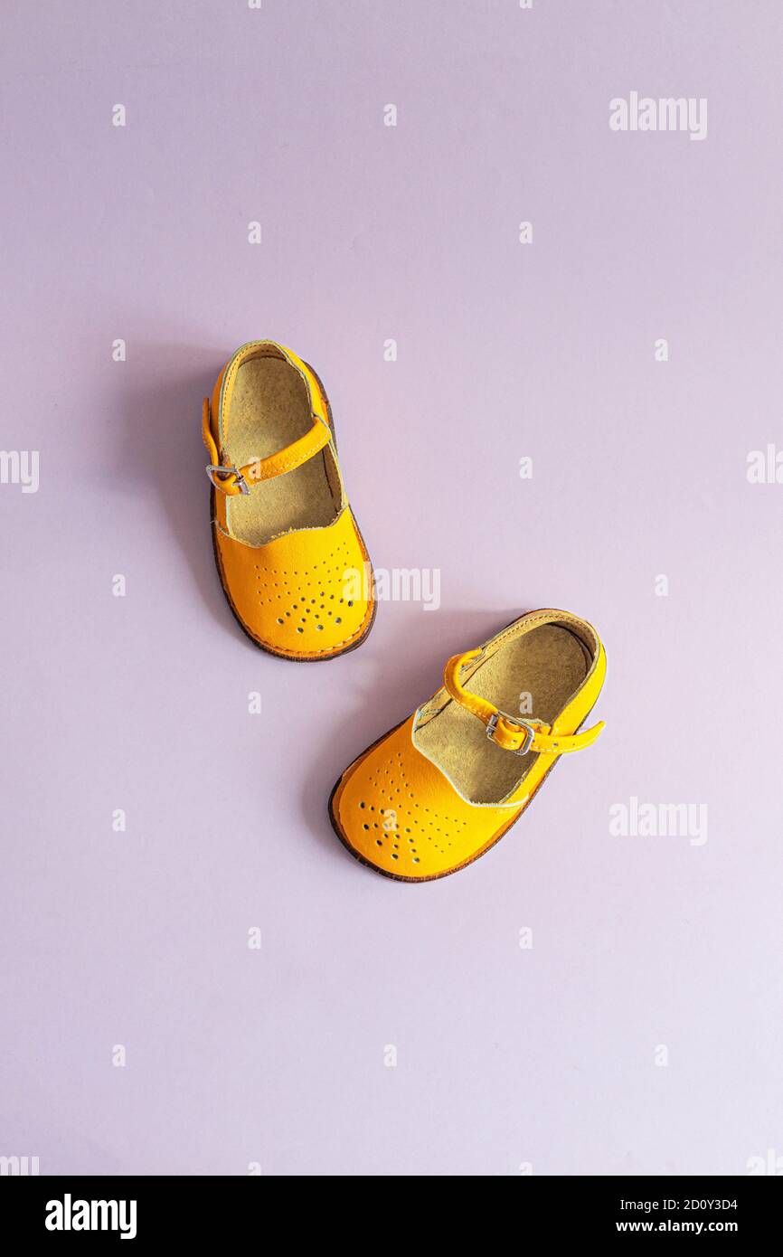 Zapatos de bebé de color amarillo brillante sobre un fondo lila con  copyspace. Concepto de ropa para bebés. Vista superior, disposición plana.  Foto vertical Fotografía de stock - Alamy