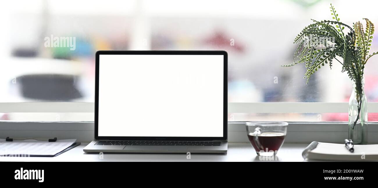 Ordenador portátil con taza de café de color blanco, documento y planta en  un espacio de trabajo mínimo Fotografía de stock - Alamy