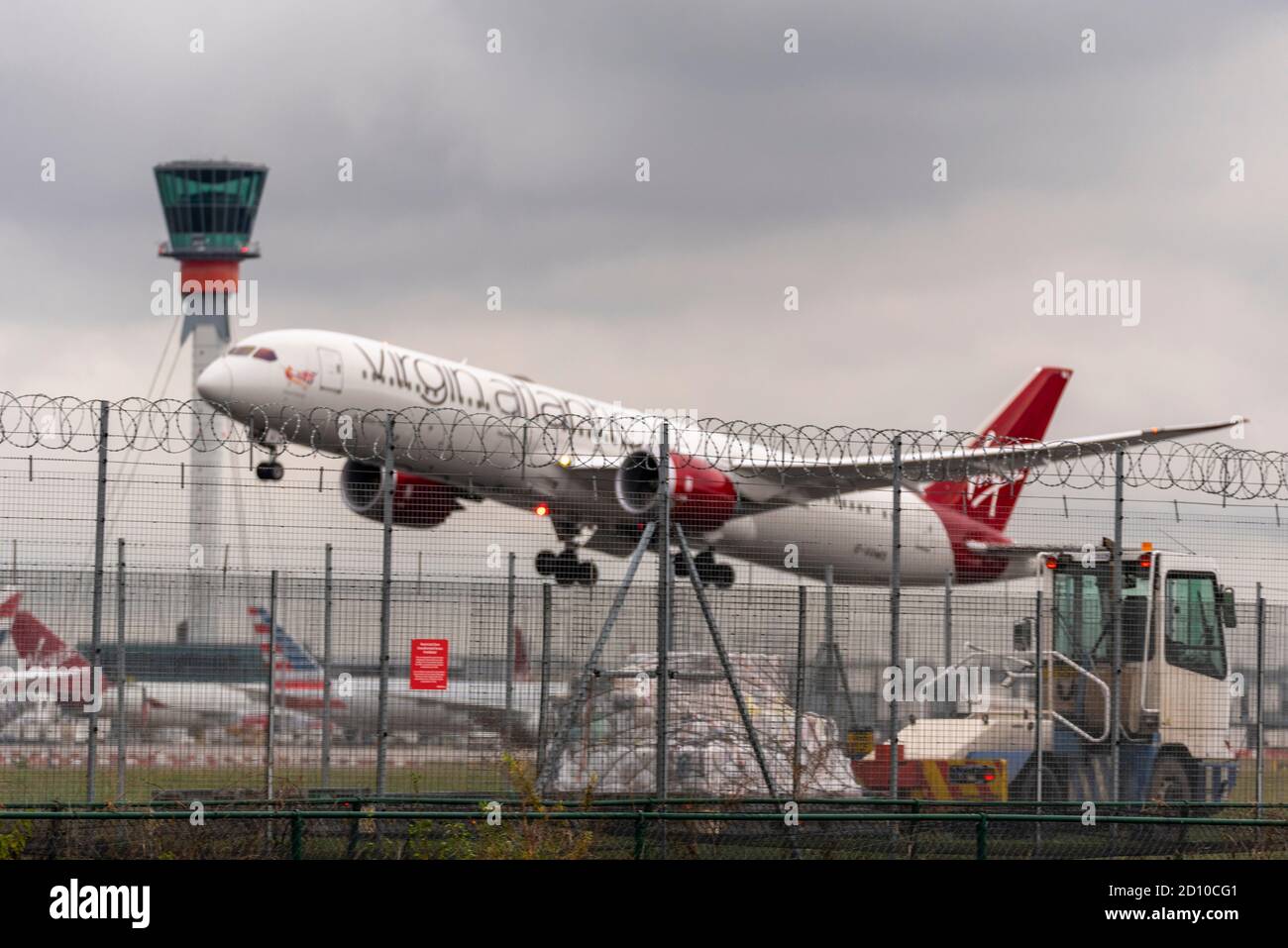 El avión de avión de avión Virgin Atlantic despegó con mal tiempo desde el aeropuerto de Heathrow, en Londres, Reino Unido, detrás de la valla de seguridad perimetral. Control del tráfico aéreo Foto de stock