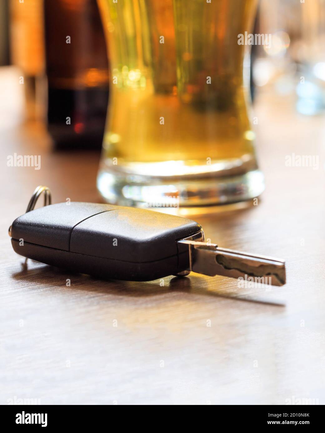 Beber y conducir, concepto dui. Llave de coche en un mostrador de pub, fondo de copas de cerveza, Vista de primer plano Foto de stock