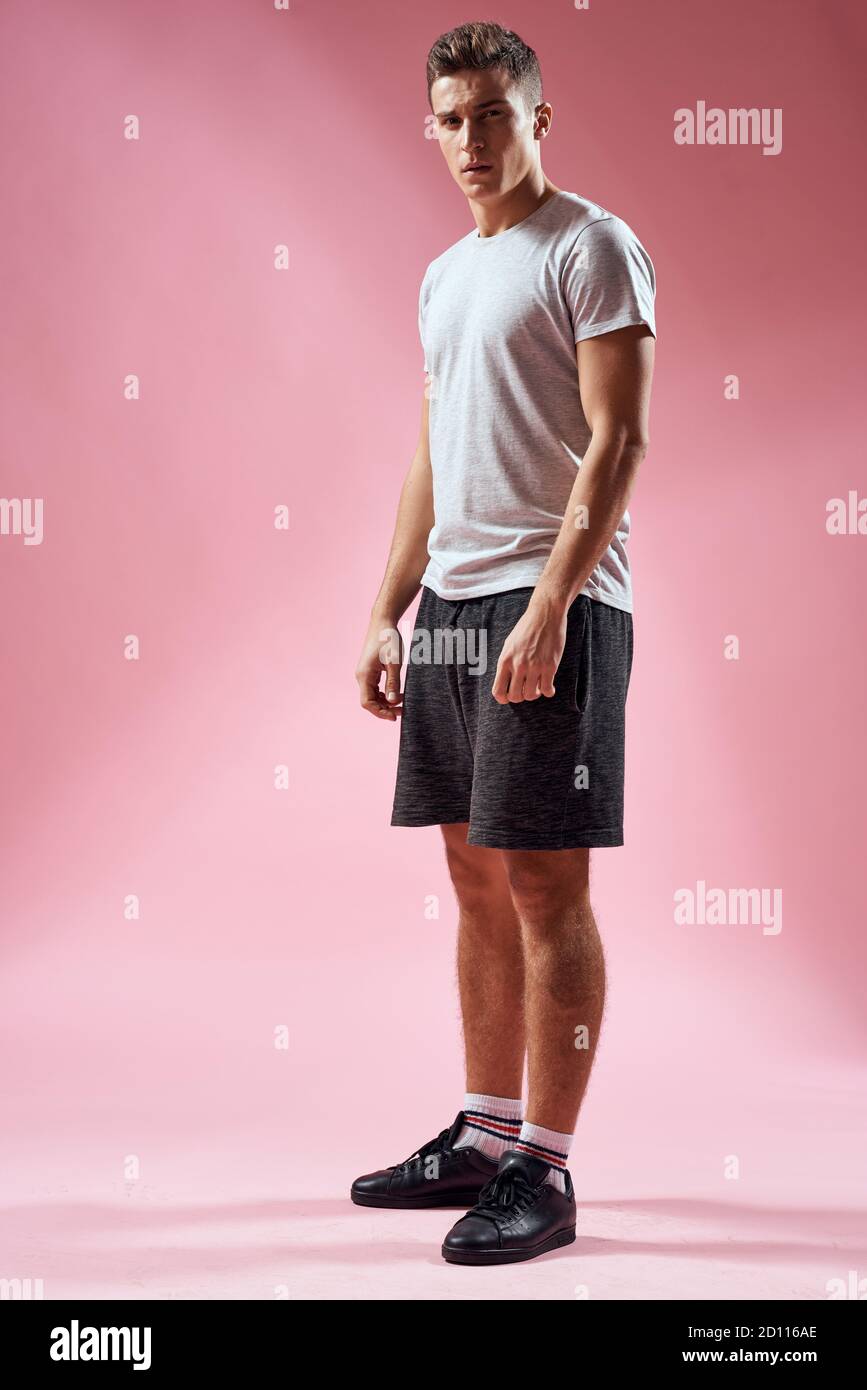 Un hombre en pantalones cortos deportivos en una camiseta y zapatillas de  deporte sobre un fondo rosa en pleno crecimiento Fotografía de stock - Alamy