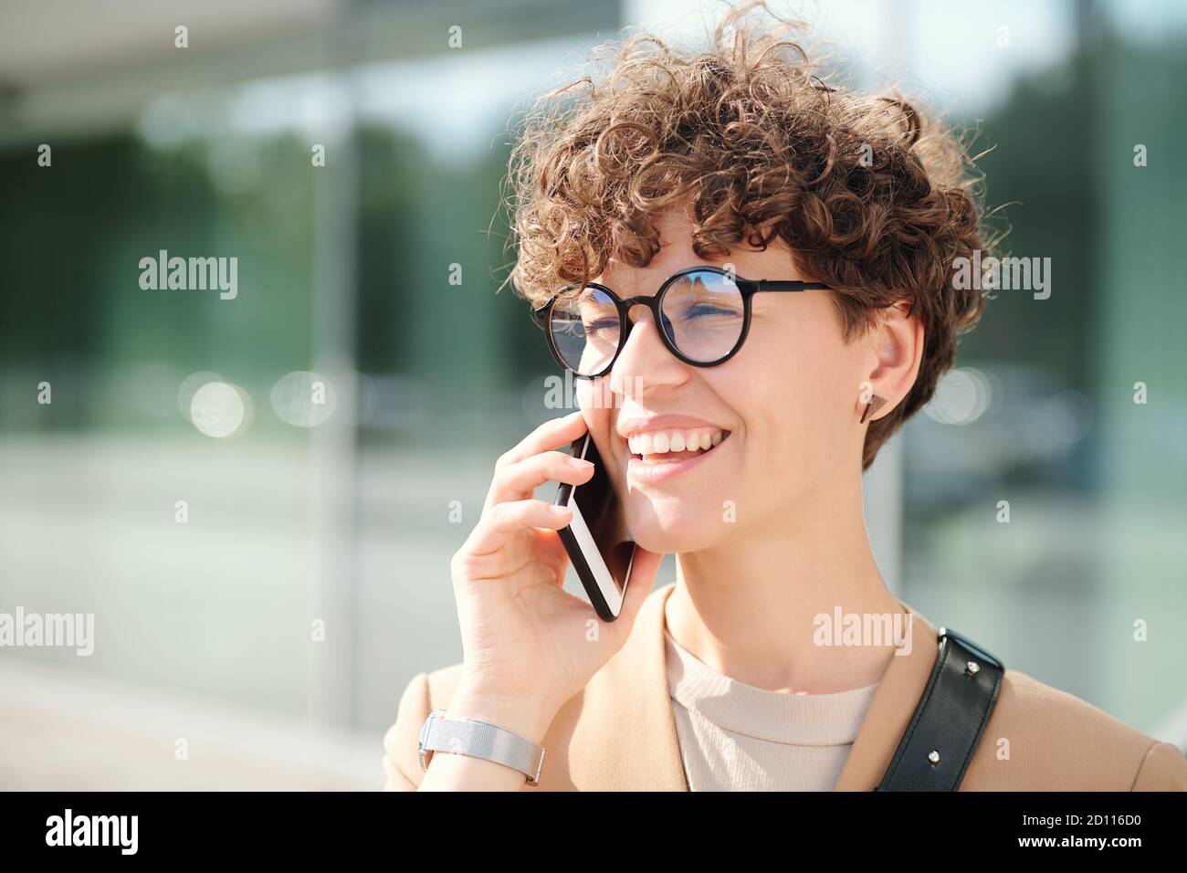 Feliz joven elegante empresaria con smartphone por cliente de consultoría de oído Foto de stock
