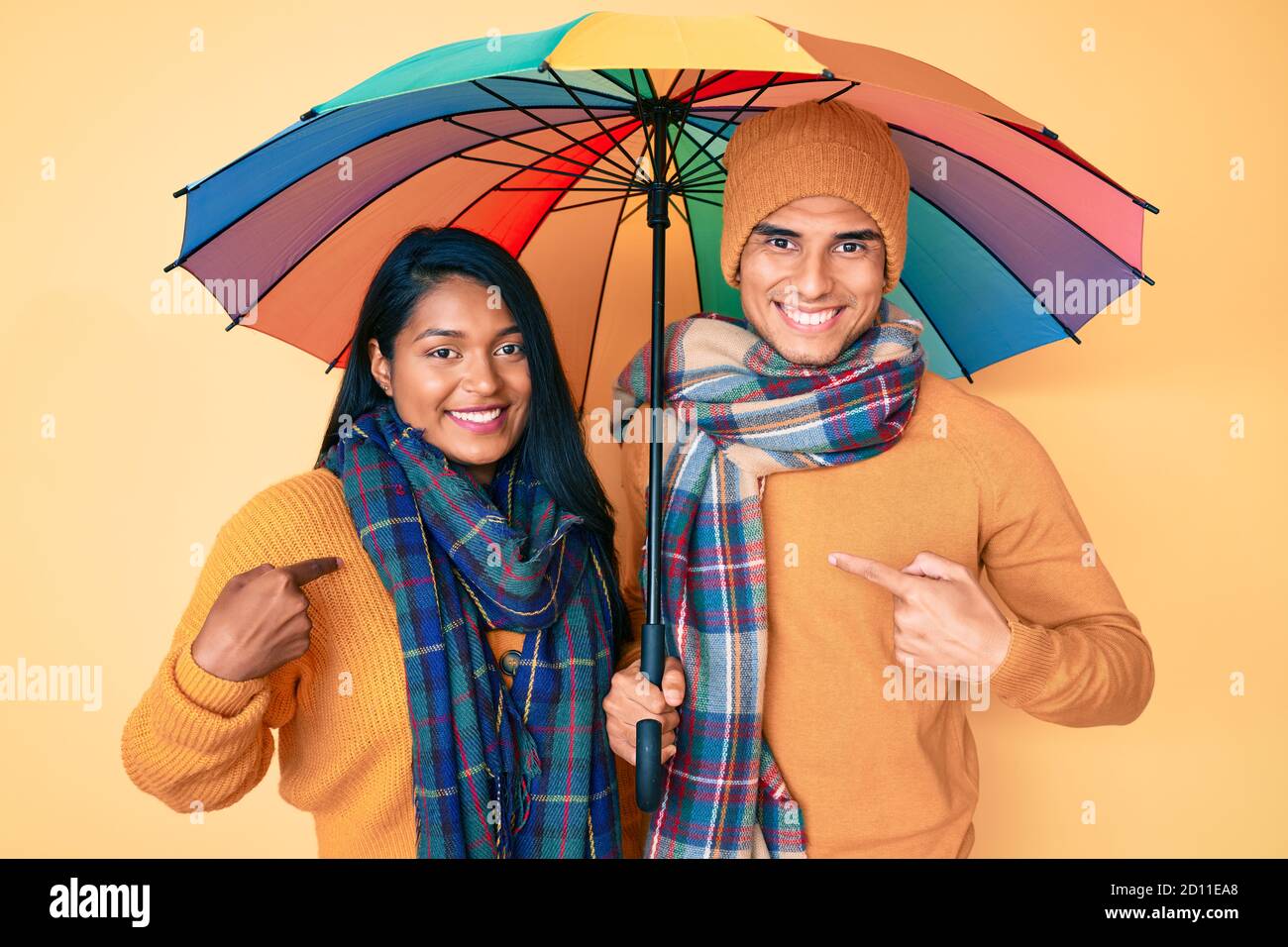 Hermosa joven latina un colorido paraguas apuntando el dedo un yo sonriendo feliz y orgulloso Fotografía de - Alamy