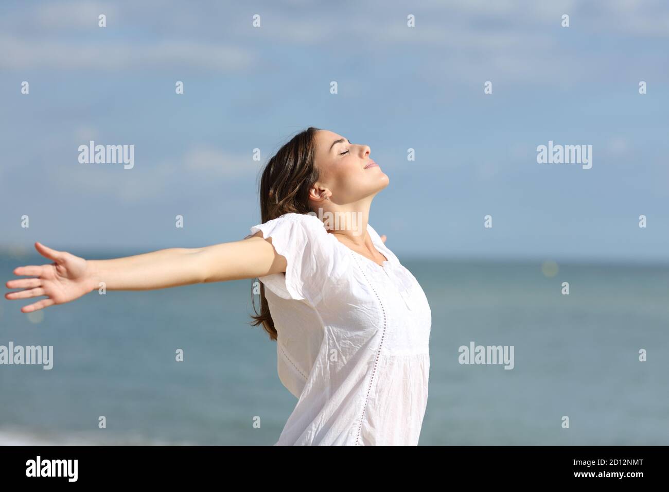 Mujer relajada en brazos blancos estirando respirar aire fresco la playa Foto de stock