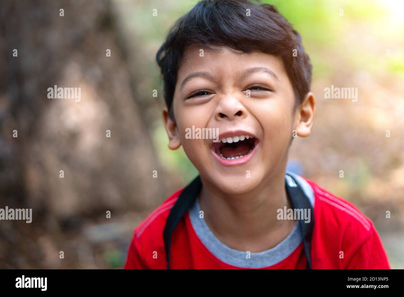 Un chico que llevaba una camisa roja se rió feliz Foto de stock