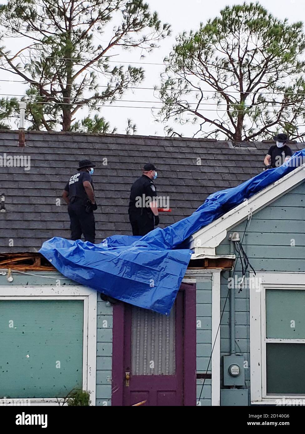 Los oficiales del CBP aplican un tarp al techo de una casa de Lake Charles, LA que había sido severamente dañado por el huracán Laura, que golpeó el suroeste de Luisiana el 26 de agosto de 2020. Foto de stock