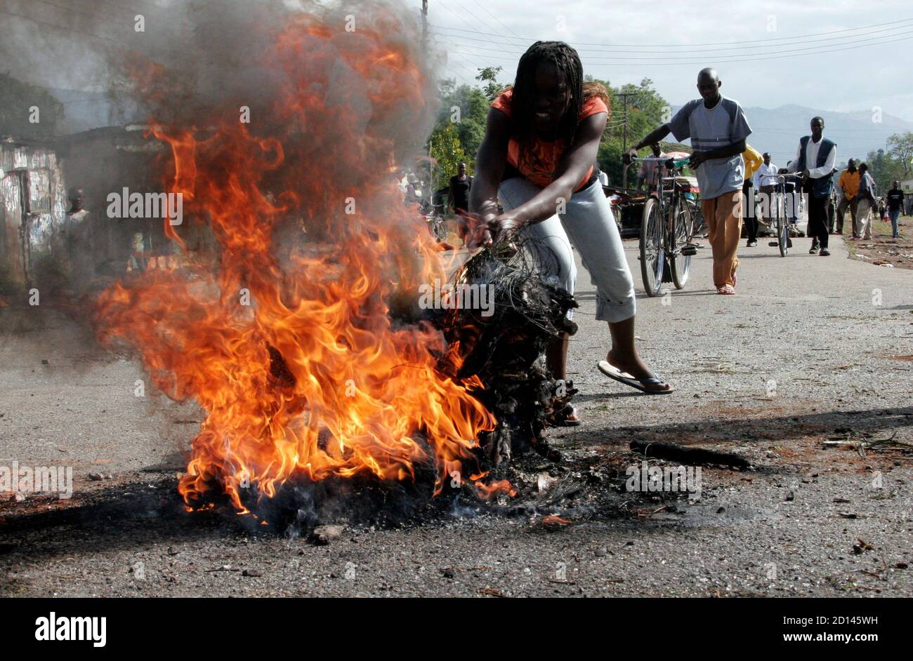 Un manifestante enciende una hoguera a lo largo de una carretera en la ciudad occidental de Kisumu el 16 de enero de 2008. Los jóvenes levantaron barricadas, los comerciantes clavaron las ventanas y la policía antidisturbios de Kenia vigiló las calles antes de las protestas de la oposición nacional previstas para el miércoles contra la reelección del presidente Mwai Kibaki. REUTERS/Thomas Mukoya (KENIA) Foto de stock