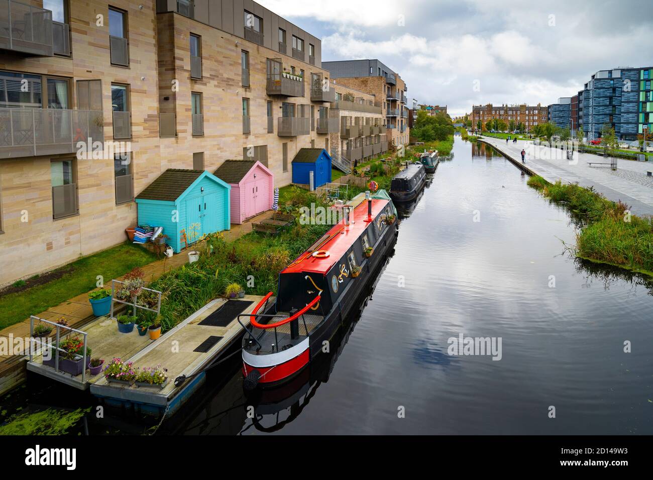 Modernos bloques de apartamentos y estrechos barcos amarrados a lo largo del Canal Unión en Fountainbridge en Edimburgo, Escocia, Reino Unido Foto de stock