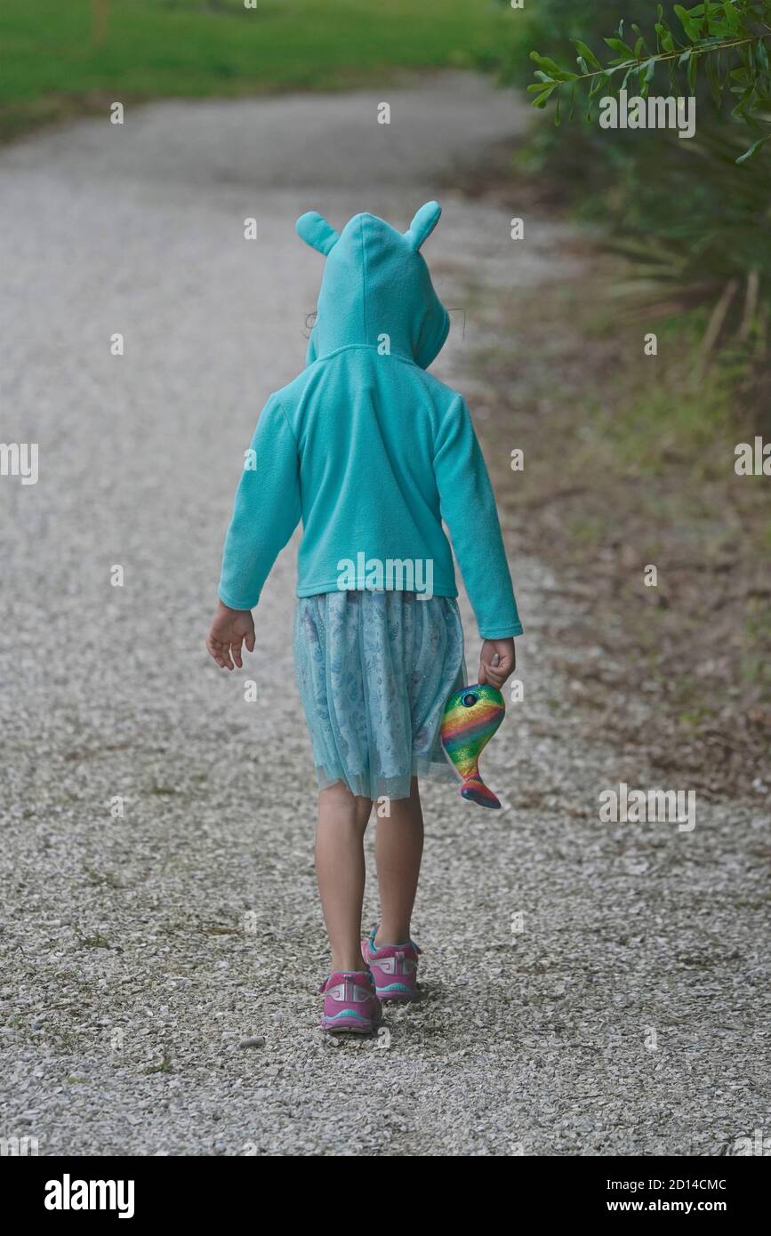 Una chica que lleva una sudadera con capucha de conejo camina por un camino Foto de stock