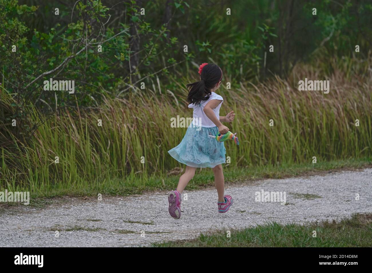 Niña de cinco años corriendo en un sendero. Foto de stock