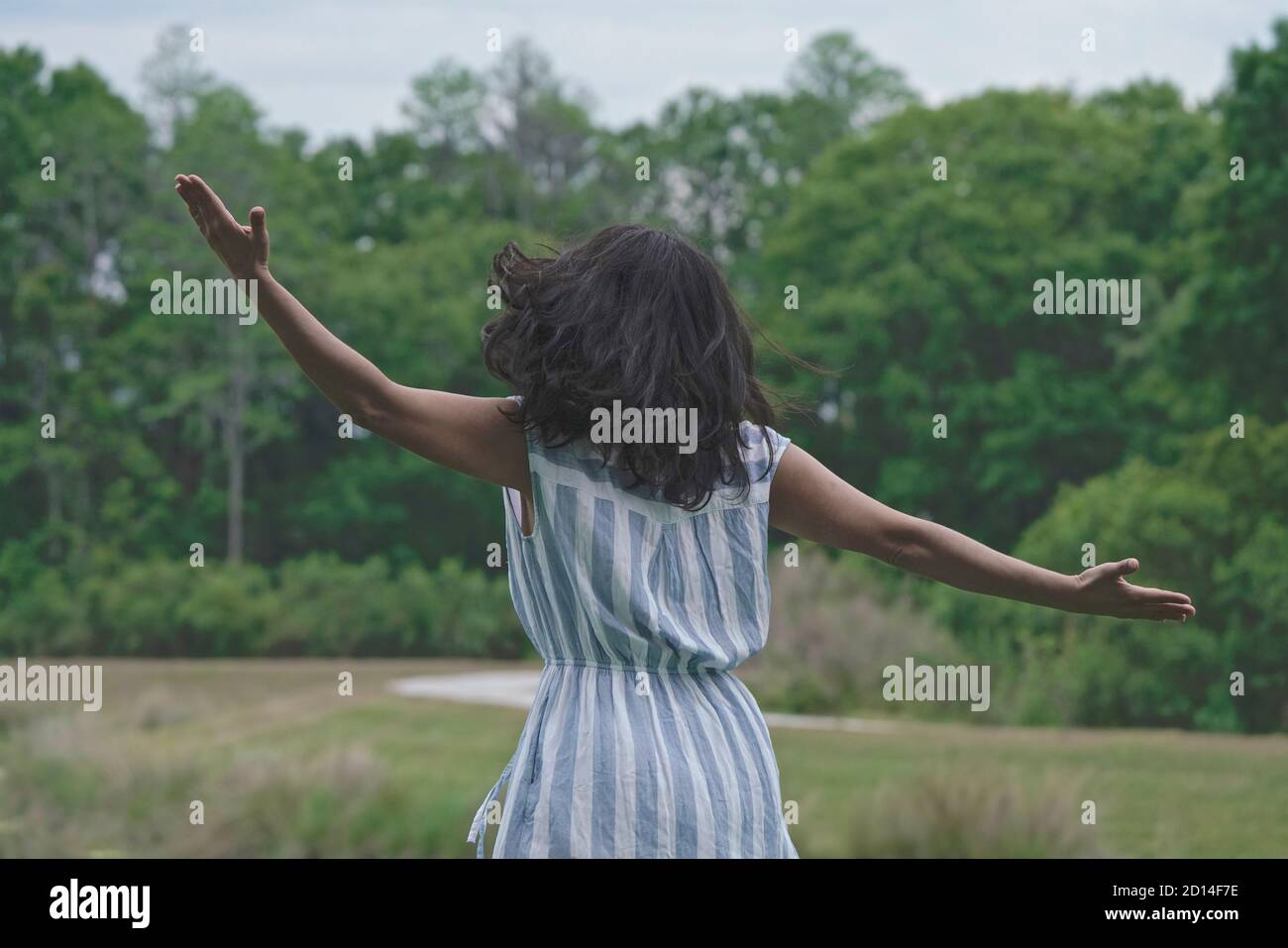 La mujer extiende sus brazos en la naturaleza, bailando con los sonidos del bosque, Foto de stock