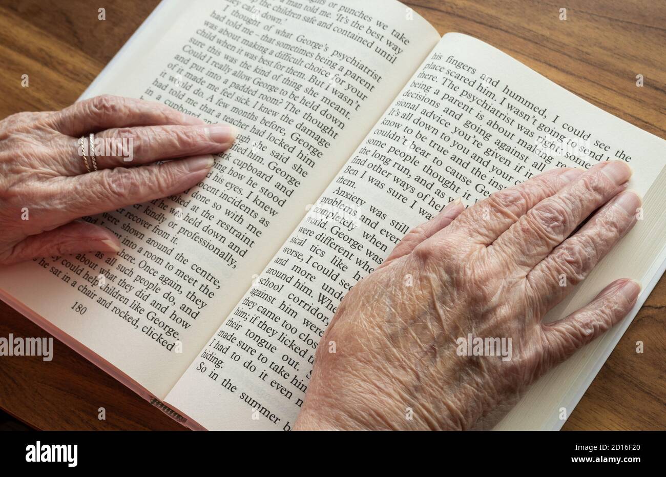 Mujer anciana con la vista deteriorada leyendo libro grande de la biblioteca impresa en casa. REINO UNIDO Foto de stock
