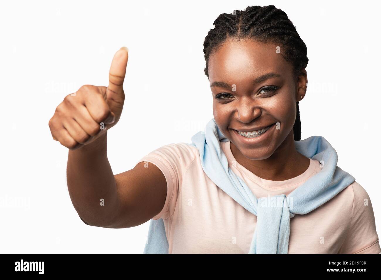 Mujer Negra Gestuing Thumbs-Up sondeando a la cámara sobre fondo blanco Foto de stock