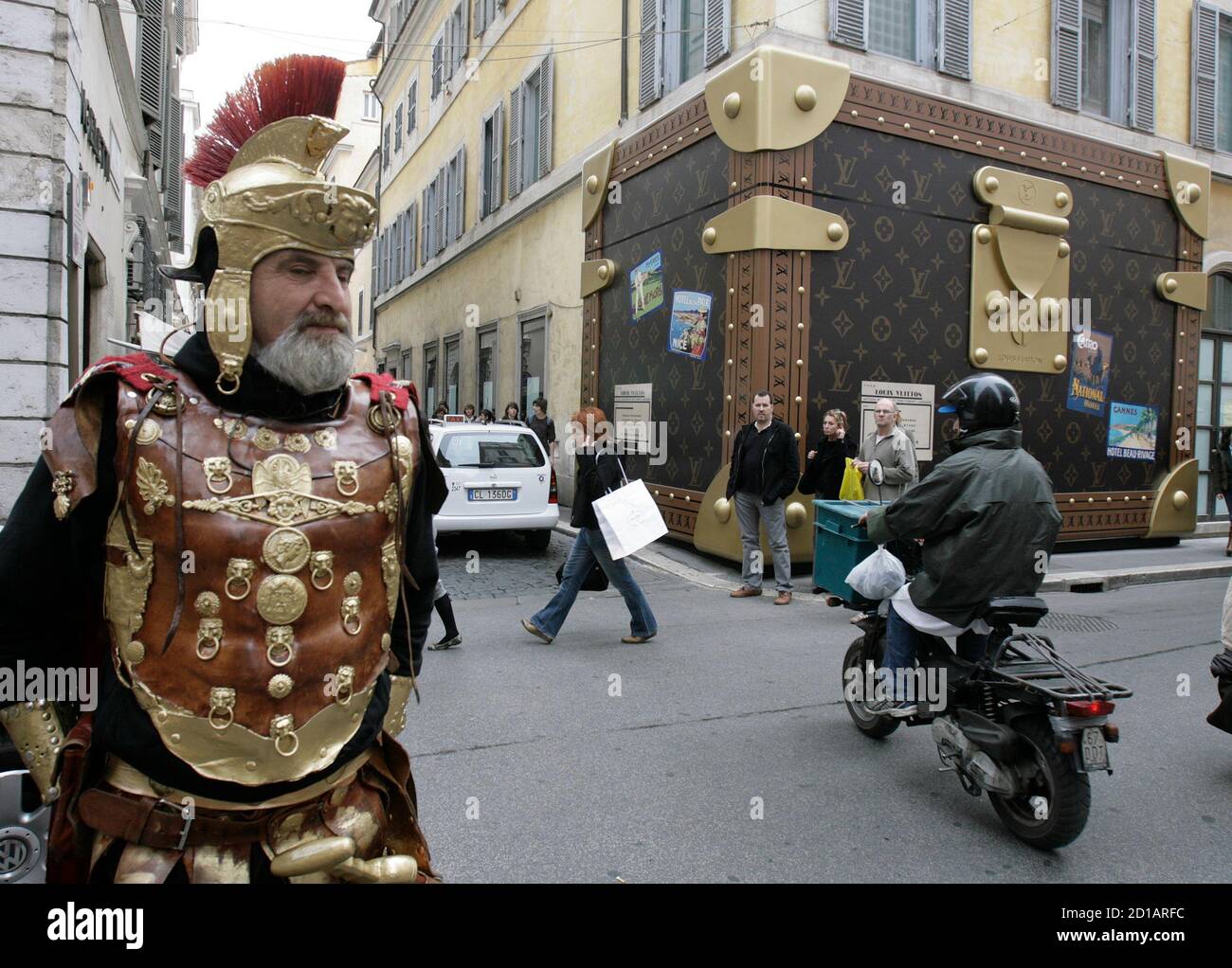 Un hombre vestido como Centurion romano pasa por una tienda Louis Vuitton cerrada por reformas, su fachada cubierta con una maleta en el centro de Roma 29 de marzo de