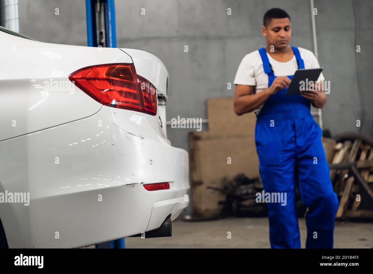 Un trabajador del taller con uniforme azul inspecciona un coche un taller  Fotografía de stock - Alamy