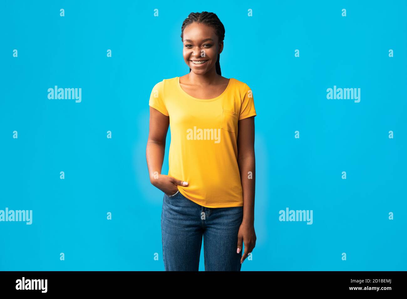 Mujer milenaria africana con escuadras de pie sobre fondo azul Foto de stock