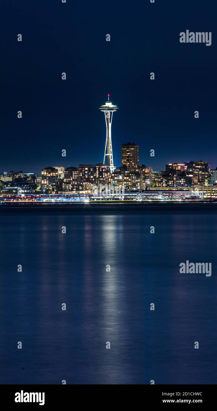 La icónica aguja Espacial y Elliot Bay en Seattle, Washington, por la noche, desde Alki Beach Foto de stock