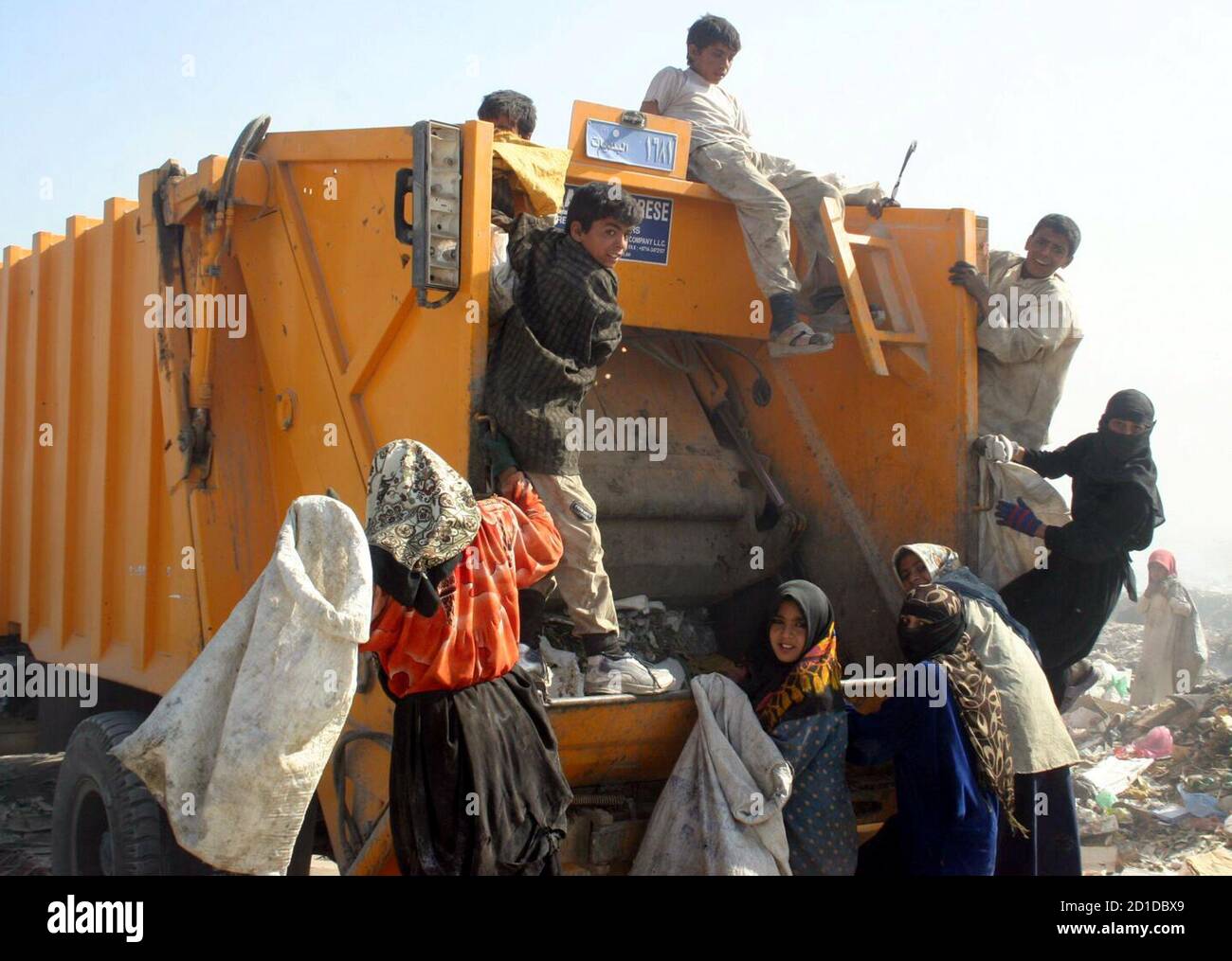 Los niños iraquíes se apresuran a solucionar un nuevo camión de basura en un vertedero en la ciudad iraquí meridional de Najaf el 15 de noviembre de 2005. El desempleo es alto y el derramamiento de sangre está alejando a los inversores de la maltrecha economía de Irak, obligando a algunos iraquíes a salir de la existencia echando basura para buscar restos de alimentos. Fotografía tomada el 15 de noviembre de 2005. REUTERS/Ali Abu Shish Foto de stock