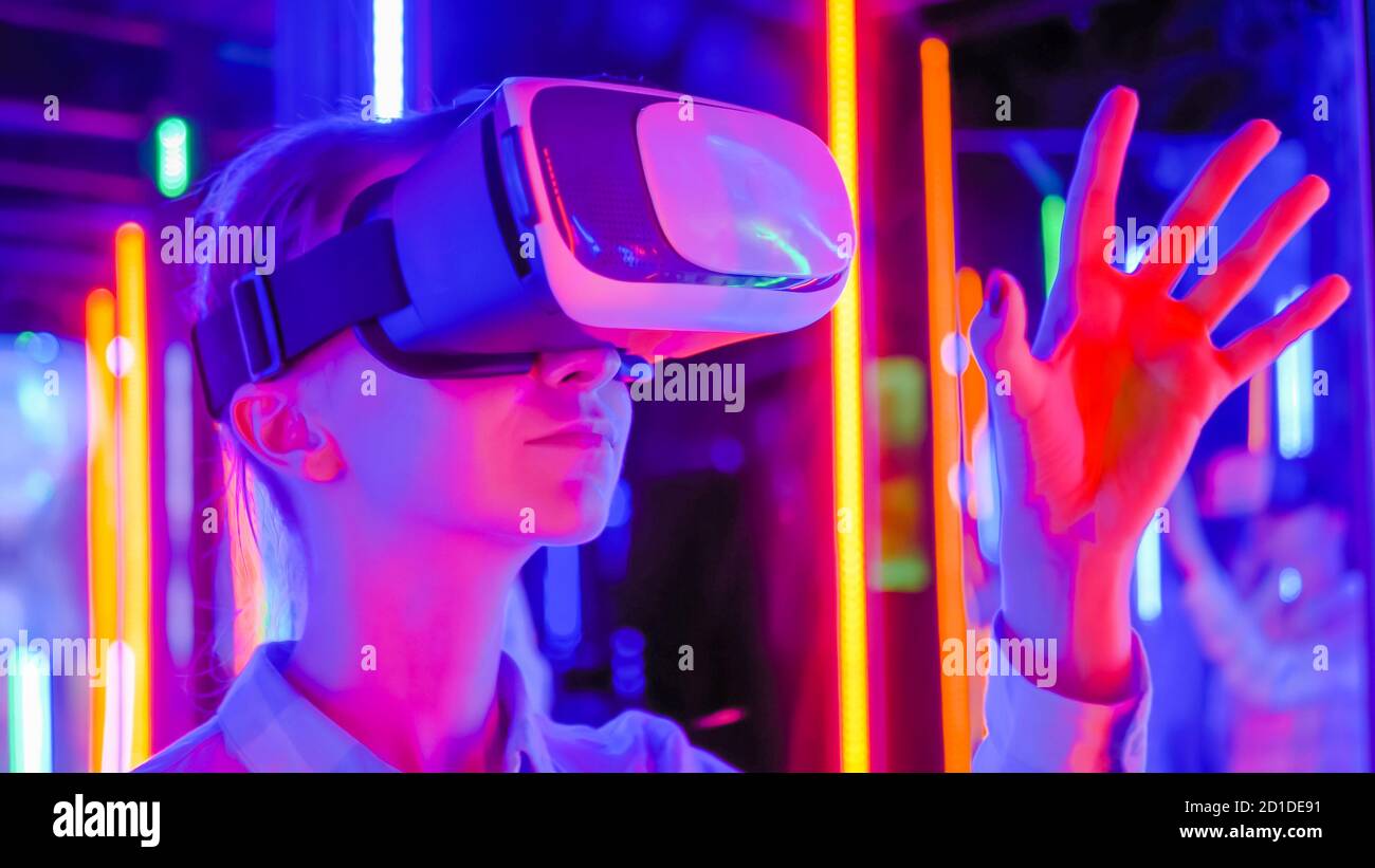 Primer plano: Mujer con auriculares de realidad virtual y mano en movimiento  en la exposición de tecnología interactiva con una iluminación colorida. VR,  futurista Fotografía de stock - Alamy
