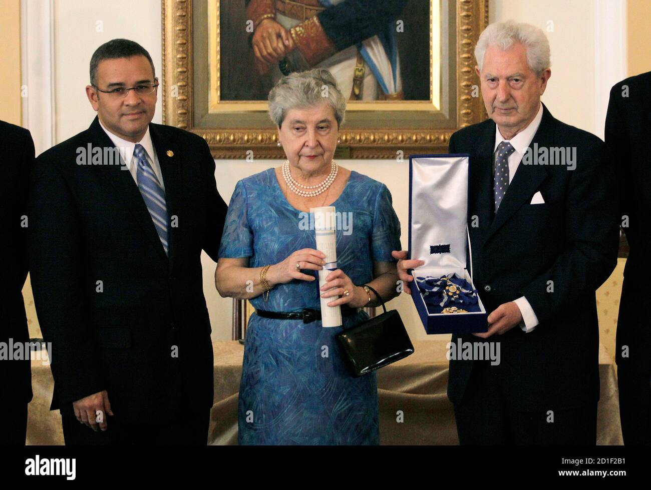 El presidente de el Salvador Mauricio Funes (L) entrega una medalla a Juan  Antonio Ellacuria (R), hermano del sacerdote jesuita nacido en España  Ignacio Ellacuria, y a su esposa Manuela Balenciaga, en