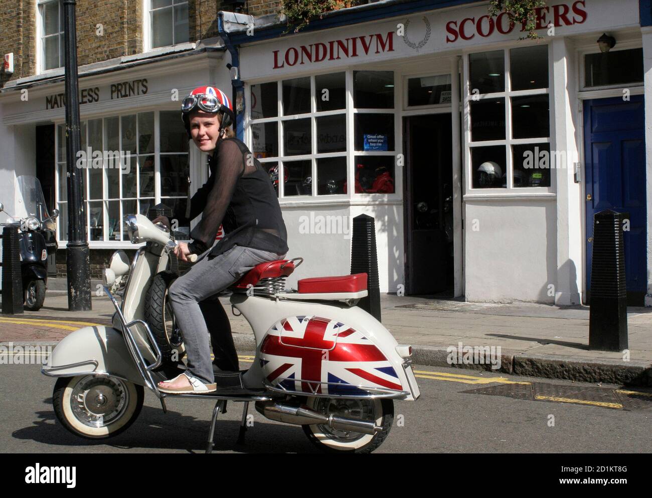 An unidentified woman poses on a vintage Vespa outside a Piaggio dealership  in London, September 27, 2006. London scooter sales have risen 16-fold to  8,000 in 2005 from 500 in 1993, especially