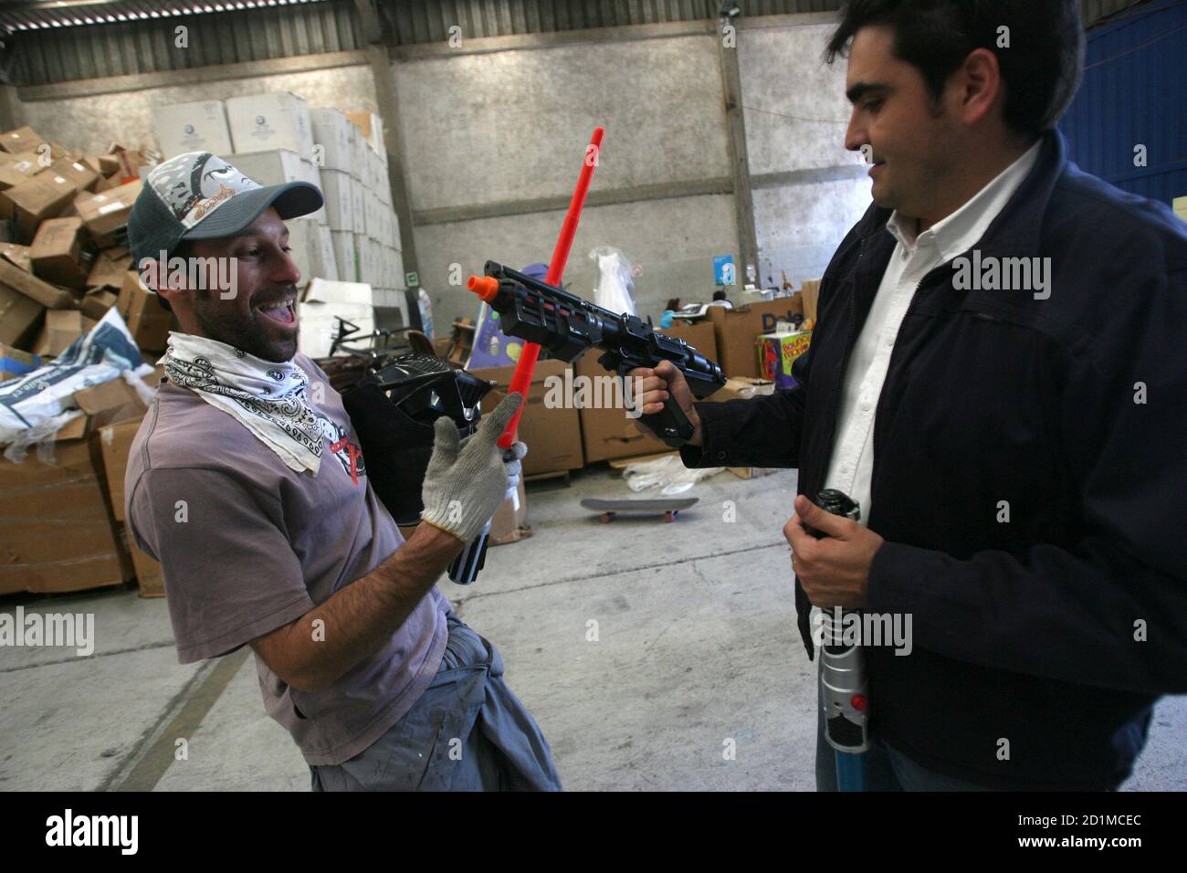 Un cliente (R) prueba una pistola de juguete mientras un trabajador sostiene una espada en una tienda de juguetes reciclados en Santiago 3 de noviembre de 2008. Más de 140 toneladas