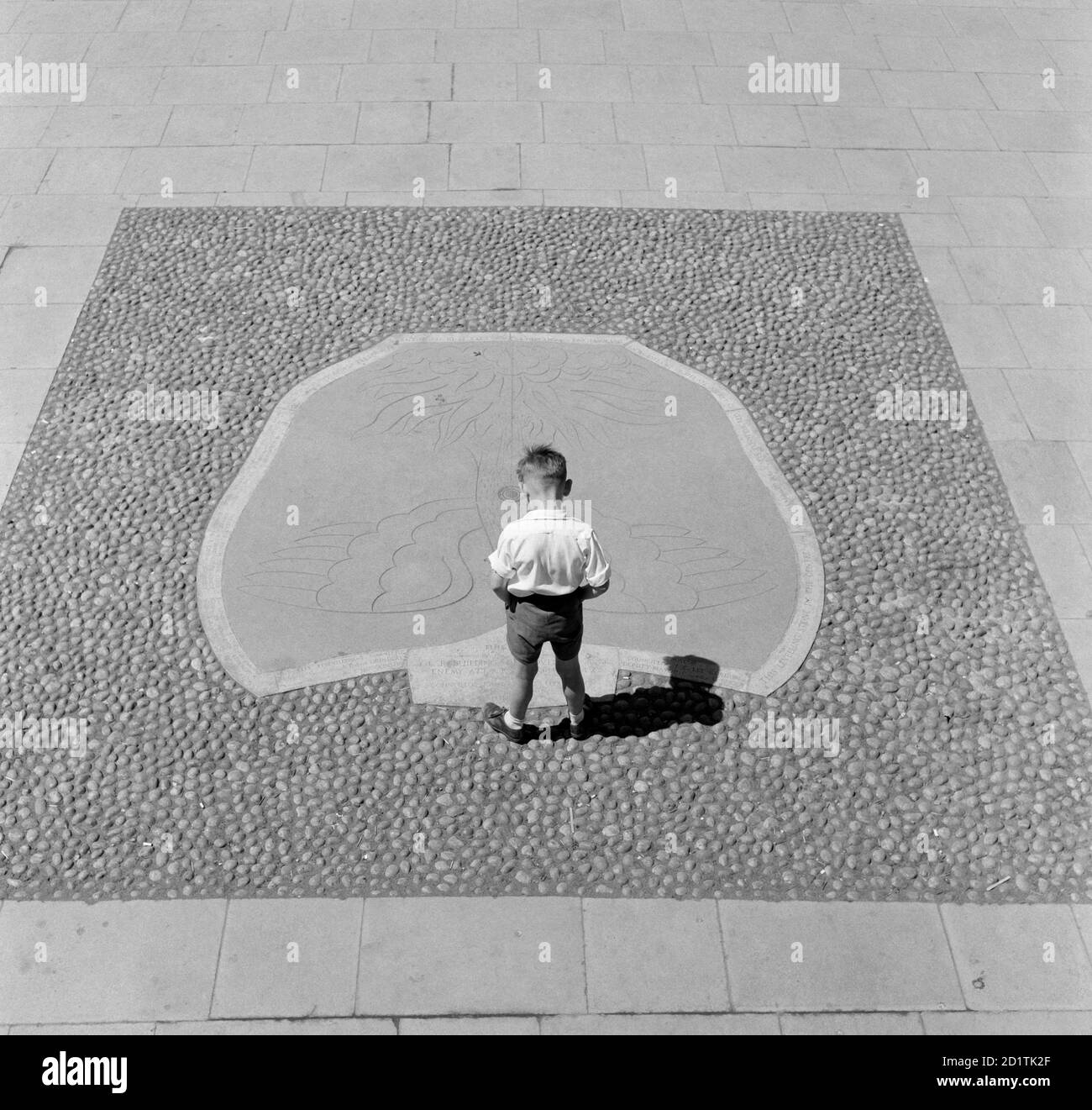 PIEDRA NIVELADORA, Coventry, West Midlands. Un niño pequeño mirando el motivo de phoenix en la Piedra de nivelación que se dio a conocer el 8 de junio de 1946 marcando el inicio de la reconstrucción del centro de la zona dañada por la guerra de Coventry. Fotografiado por Eric de Mare entre 1960 y 1969. Foto de stock