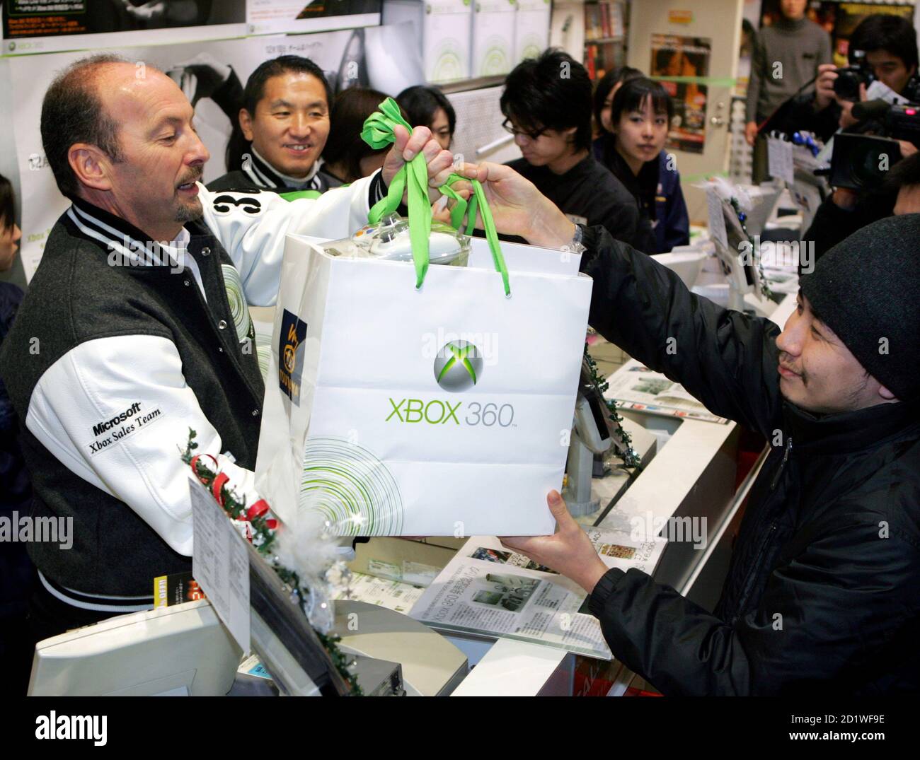 Microsoft Corp's Corporate Vice President of Worldwide Marketing and  Publishing Peter Moore (L) hands the company's new Xbox 360 video game  console to a Japanese customer over the counter after an early