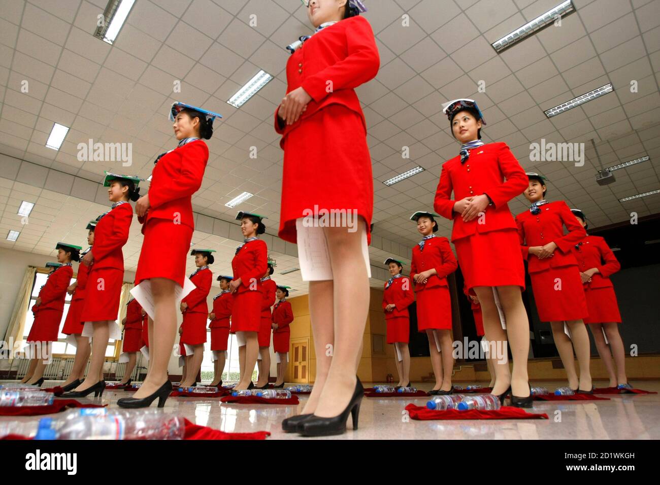 Students hold a piece of paper between their legs as they balance a book on their heads during etiquette training at a vocational school in Beijing October 25, 2007. Around 1,400 aviation service students, mostly between the ages of 16 and 17, are currently going through physical conditioning as well as professional training for dressing and etiquette in order to serve as the stewards during the 2008 Beijing Olympics, according to the school announcement. REUTERS/Jason Lee (CHINA) Foto de stock