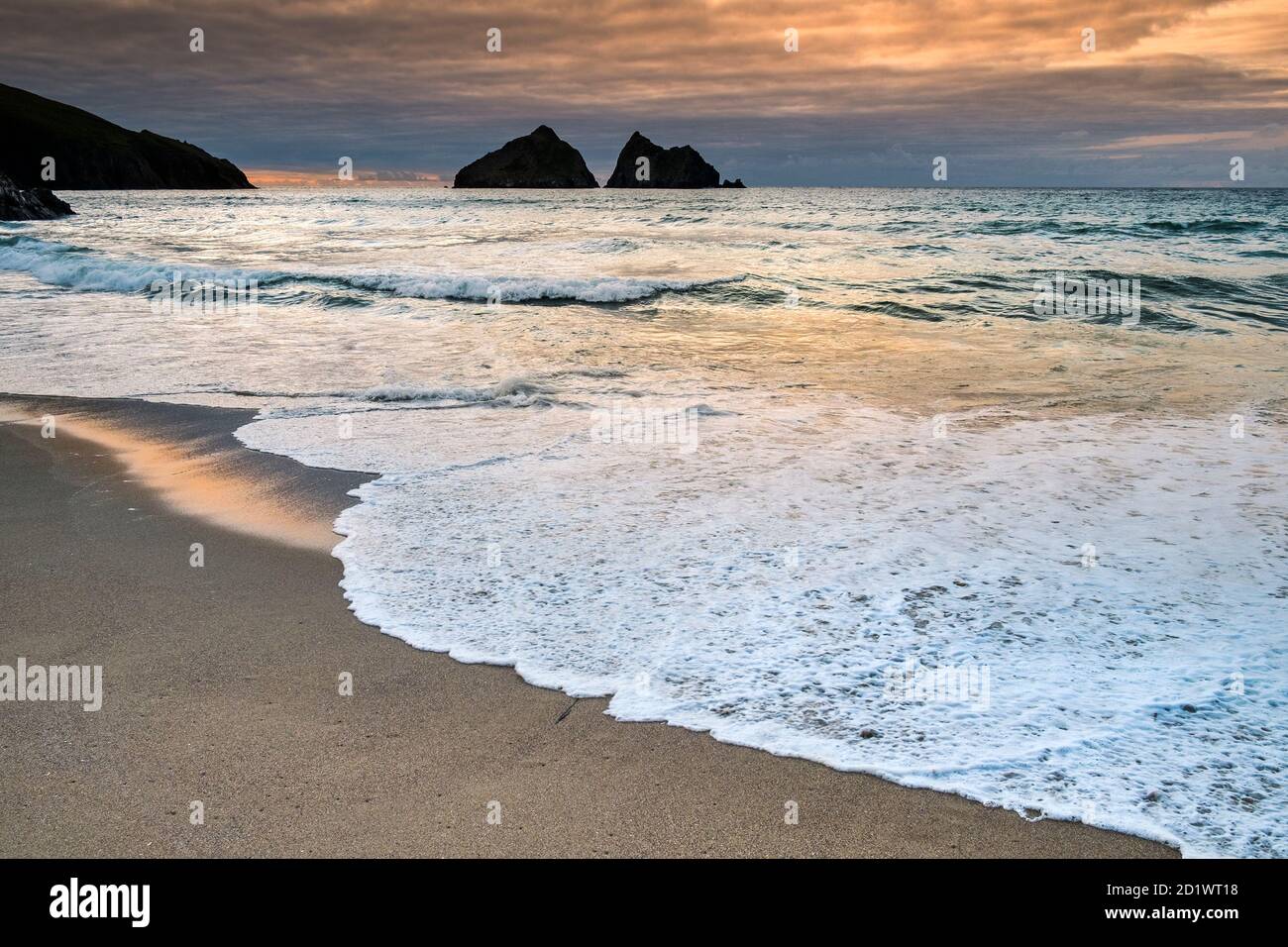 Puesta de sol en Holywell Beach con Gull Rocks en la distancia en Cornwall. Foto de stock