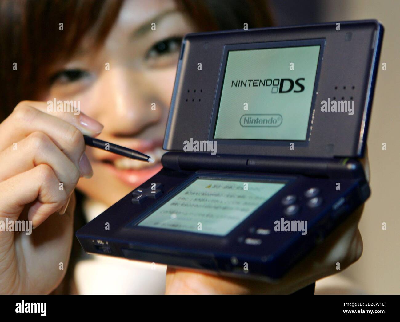 A Japanese model shows off Nintendo Co.'s new dual screen handled video  game console "Nintendo DS Lite" at an unveiling in Tokyo February 15, 2006.  The 218-gram (7.69-ounce) game console will start