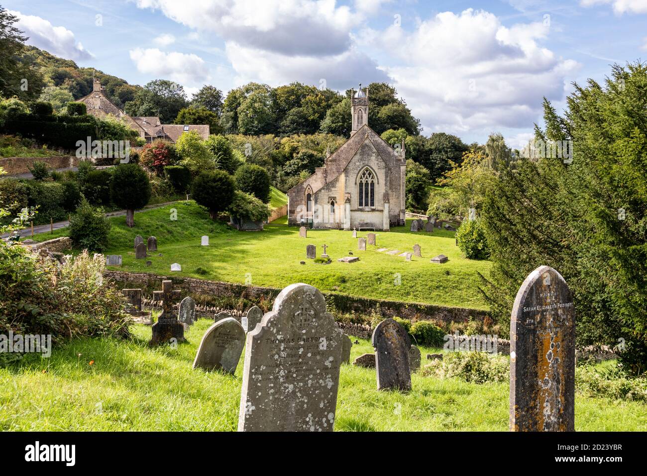 La iglesia de San Juan en el pueblo Cotswold de Sheepscombe, Gloucestershire Reino Unido - el cementerio está dividido por un carril hundido. Foto de stock