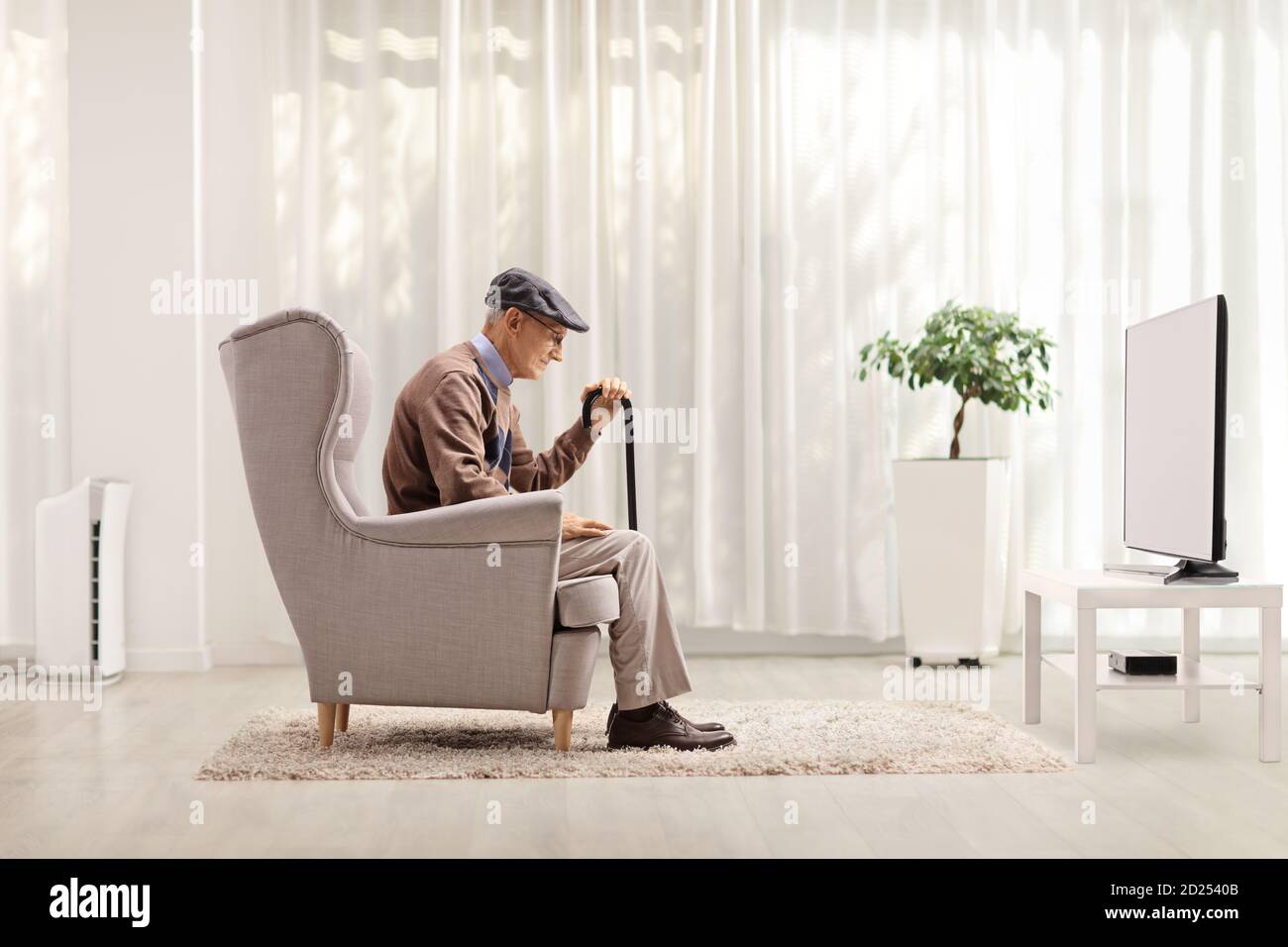 Triste anciano solitario sentado en un sillón en casa Foto de stock