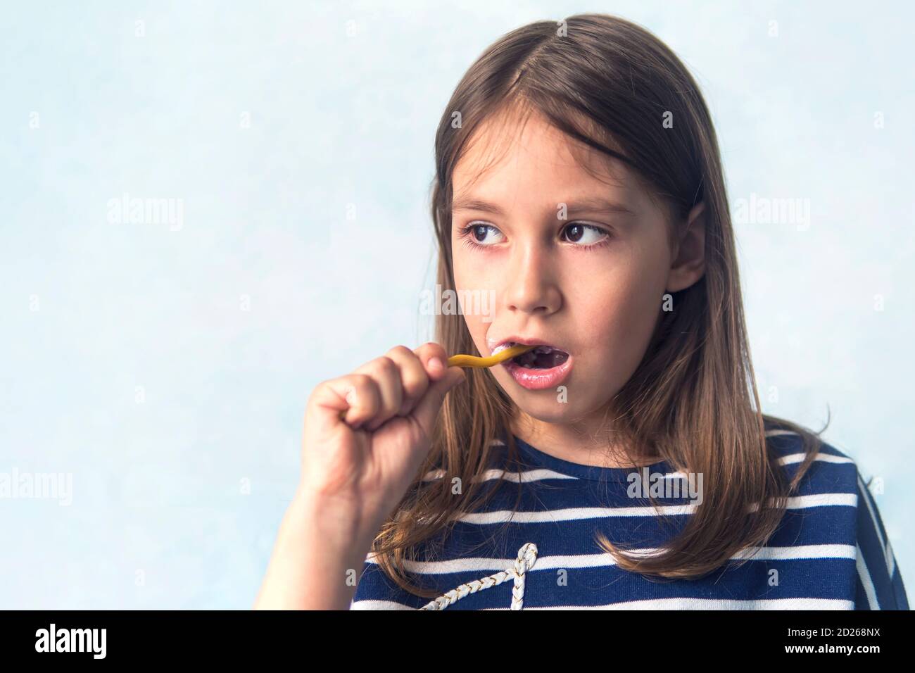 Una niña de apariencia caucásica cepillándose los dientes con un cepillo de dientes, procedimientos de higiene por la mañana... sonriendo a niños pequeños mientras la cepillaba Foto de stock