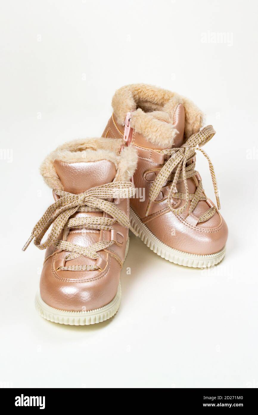 botas de invierno para niños con cordones y piel para niñas, piel rosa  artificial y cordones lurex, foto vertical. Zapatos hermosos para un niño,  botas de calor para Fotografía de stock -