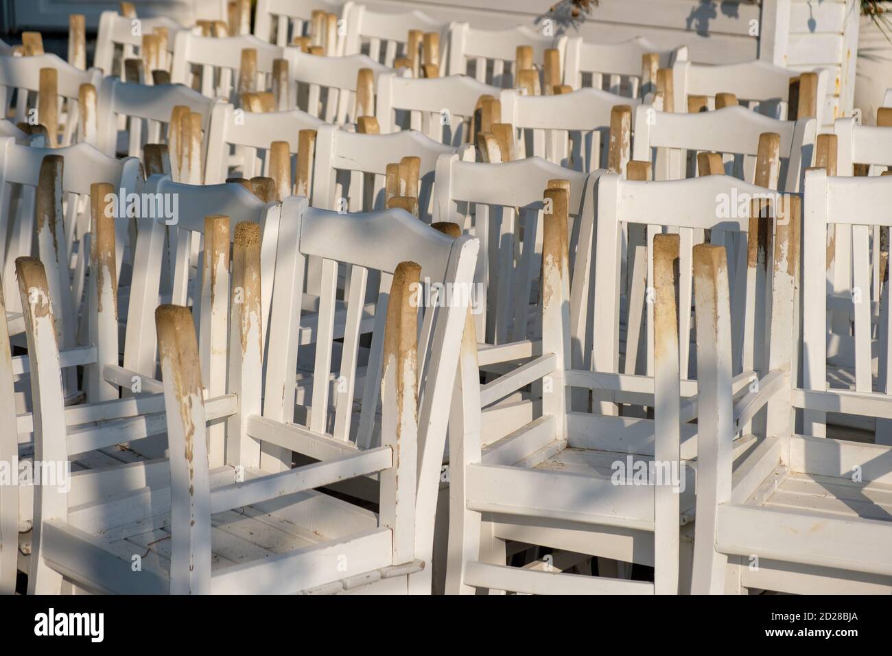 Primer plano de un montón de sillas blancas al revés Foto de stock