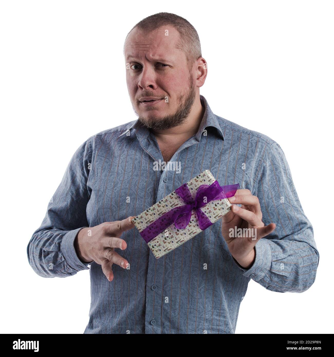 actor emocional hombre en una camisa gris con una caja con un regalo en las manos posando sobre un blanco fondo en el estudio Foto de stock