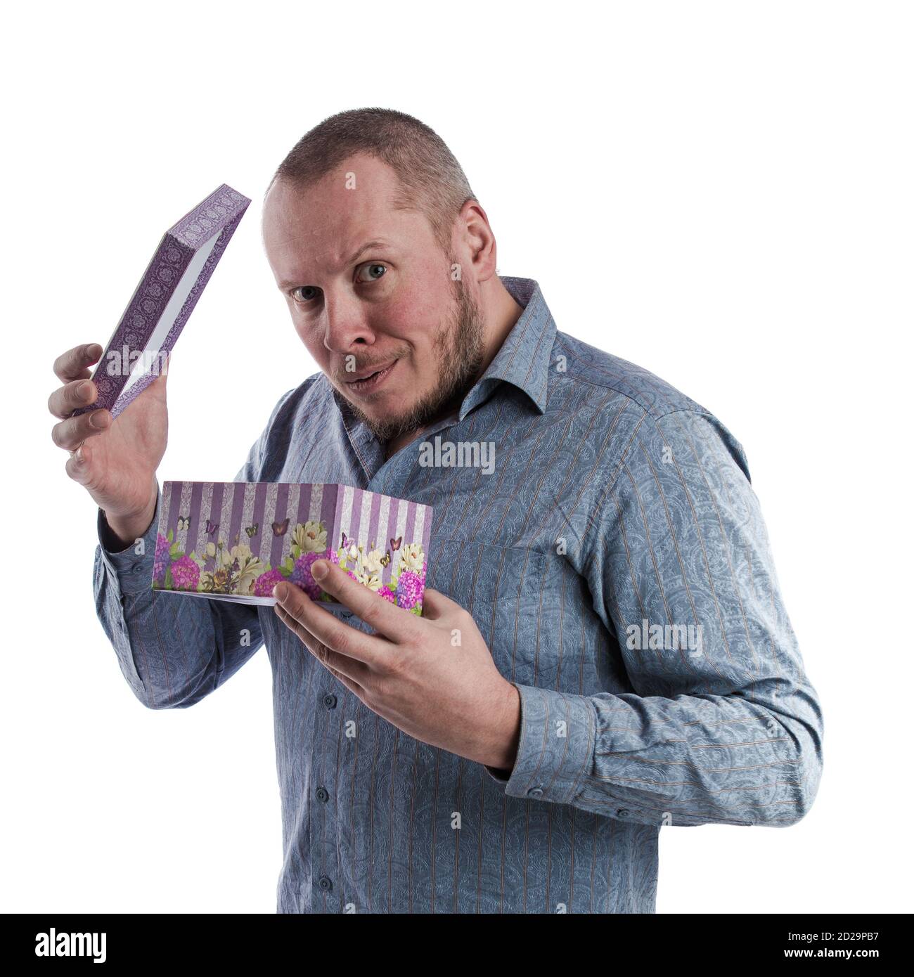actor emocional hombre en una camisa gris con una caja con un regalo en las manos posando sobre un blanco fondo en el estudio Foto de stock