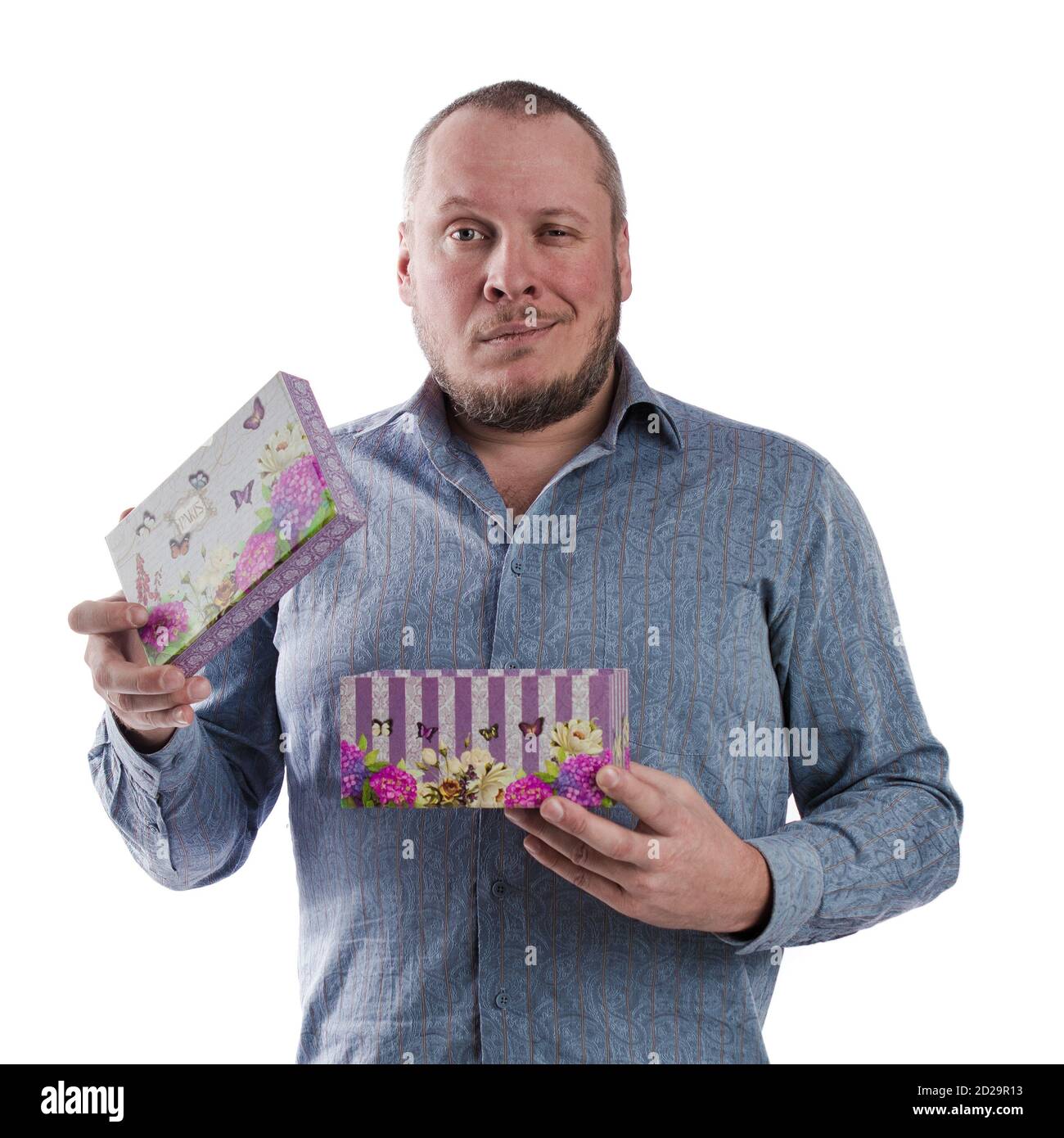 actor emocional hombre en una camisa gris con una caja con un regalo en las manos posando sobre un blanco fondo en el estudio Foto de stock