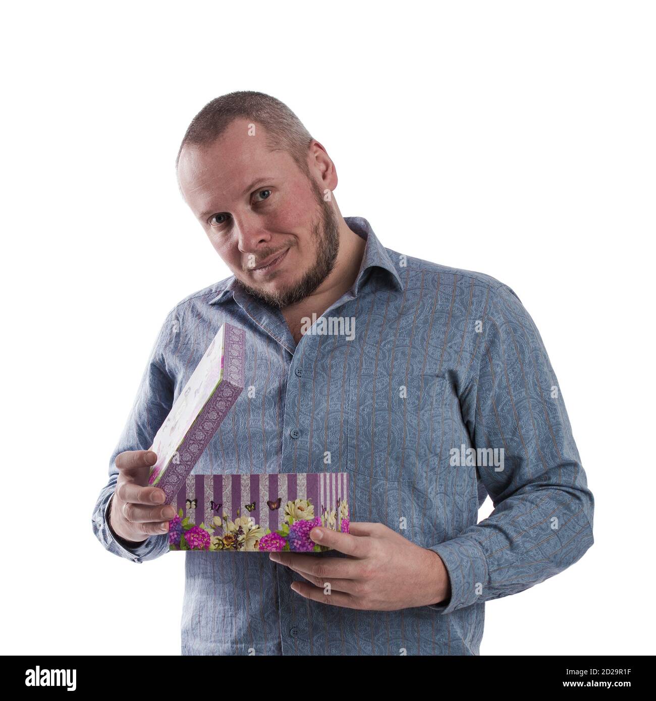 actor emocional hombre en una camisa gris con una caja con un regalo en las manos posando sobre un blanco fondo en el estudio Foto de stock