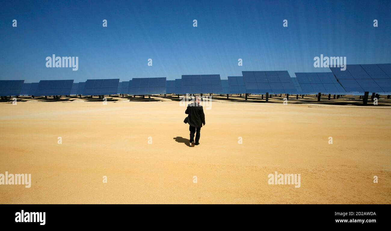 Un hombre camina en el parque solar 'solar' en Sanlúcar la mayor, cerca de Sevilla, 23 de septiembre de 2009. La planta de energía solar térmica utiliza espejos para concentrar los rayos del sol en las torres donde producen vapor para conducir una turbina, produciendo electricidad. REUTERS/MARCELO DEL POZO (ESPAÑA ENERGÍA MEDIO AMBIENTE SOCIEDAD IMÁGENES DEL DÍA) Foto de stock