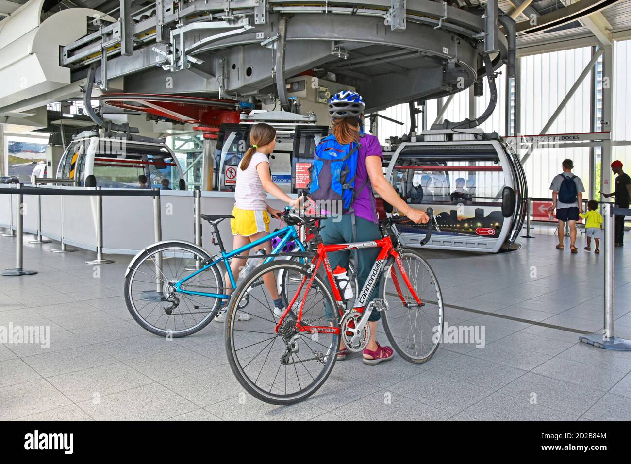 El ciclista y su bicicleta esperan a subir al transporte para Londres Emirates Air Line cable car pareja ciclistas y bicicleta de viaje Río Támesis, Inglaterra, Reino Unido Foto de stock