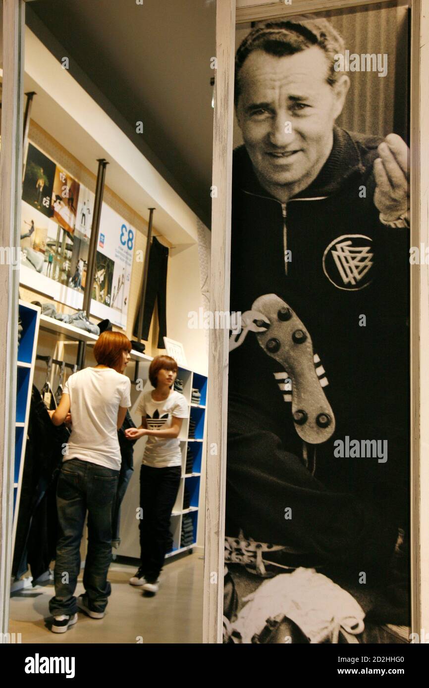 Staff arrange apparel near a photograph of Adidas founder Adolf 'Adi'  Dassler at the new and world's largest Adidas Brand Center store in Beijing  July 3, 2008. Adidas will open its world's