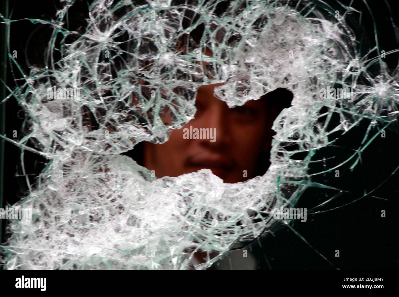 A fashion store employee is seen through a broken shop window in Bangkok May 26, 2010. A Thai court issued orders on Tuesday to arrest former Prime Minister Thaksin Shinawatra on terrorism charges in connection with riots over the past two months that were the worst in the country's modern history. REUTERS/Yannis Behrakis (THAILAND - Tags: CIVIL UNREST POLITICS BUSINESS) Foto de stock