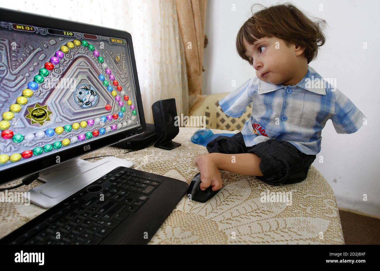 Ali Srour juega juegos en el ordenador de su padre con los pies en la casa  de sus padres en Amman 9 de junio de 2010. Ali nació sin armas, pero ha