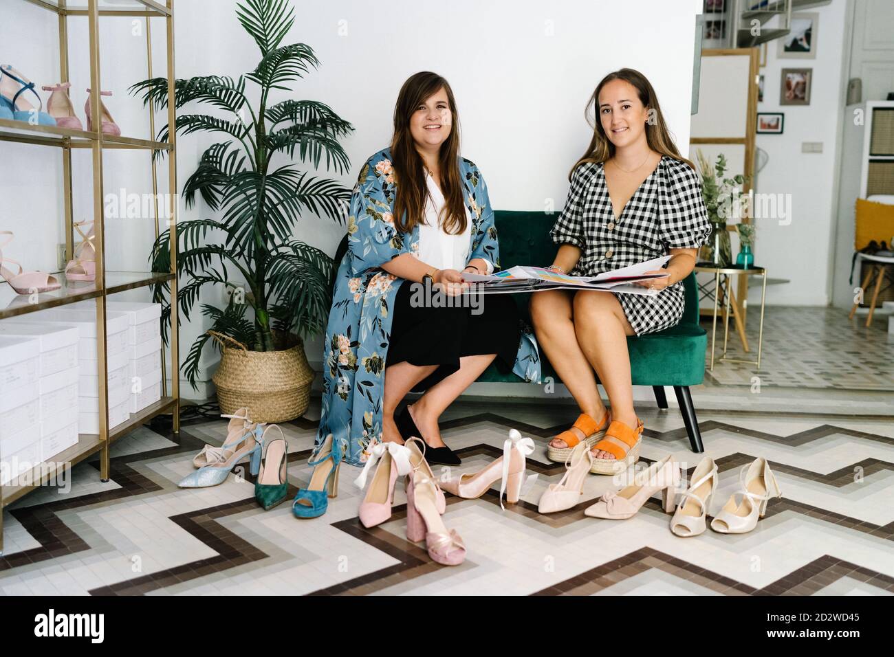Ocupada diseñadoras sentadas en el sofá y mirando la cámara en una boutique  cara con una nueva colección de moda de alta tacón zapatos Fotografía de  stock - Alamy